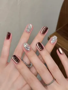 Close-up of wine red and silver glitter press-on nails with sparkling diamond accents