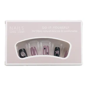 Short purple and black cat-eye press-on nails with star patterns in retail packaging