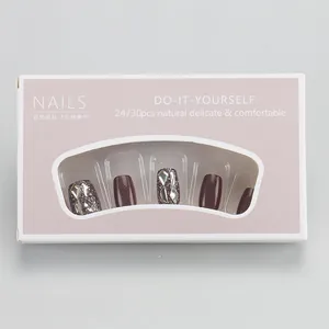 Detail view of brown press-on nails set with glitter and diamonds in pink window box