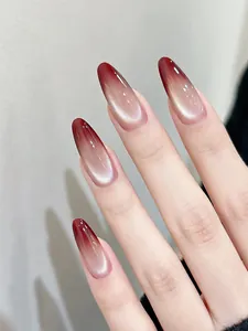Dettaglio di unghie finte ovali lunghe con sfumatura bordeaux cat-eye e riflessi