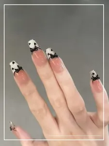 Detail of pink and white gradient coffin nails with black 3D bows and heart patterns