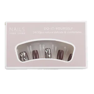 Short press-on nails in coffee brown with glitter and silver rhinestones in a gray box