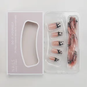Nude pink press-on nails set with black bows and heart patterns in lavender box