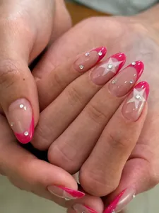 Detailed close-up of almond-shaped French nails with rose red tips and star star accents