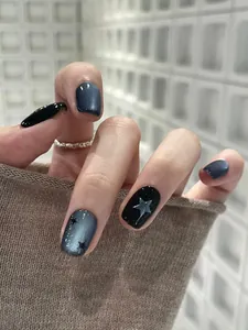 Detailweergave van donkerblauwe kattenoog plaknagels met zilveren sterren op zwart