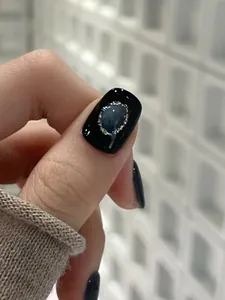 Macro-opname van zwarte cat-eye nagel met blauwe edelsteen en zilveren glitteraccenten