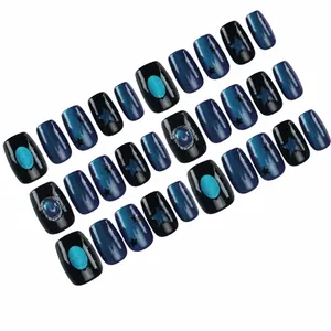 Korte press-on nagels met blauw kattenoogeffect, zwarte sterren en 3D-edelstenen