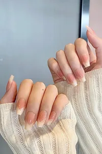 Close-up of nude pink gradient coffin press-on nails with white French V-shaped tips