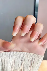 Macro shot of French tip press-on nails in nude pink and beige with a coffin shape finish