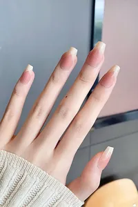 Close-up of coffin-shaped pink ombre French tip press-on nails on a model hand