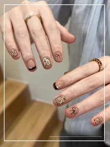 Detail of autumn cat-eye press-on nails with leopard patterns and pearl french tips