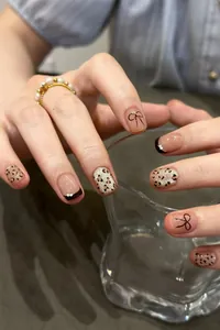 Detail view of cat eye leopard print press-on nails with French tips and bow accents