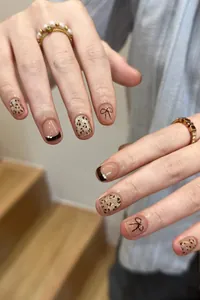 Detail of luxury press-on nails featuring leopard print, French pearls, and chic bows