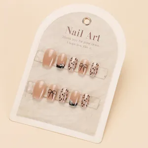 Chic press-on nail set featuring leopard print, bows, and rhinestones on beige base
