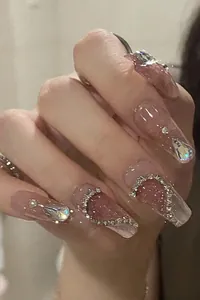Macro shot of pink heart press-on nails with sparkling rhinestones and cat-eye glitter