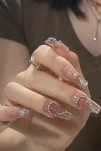 Detail of pink cat-eye coffin nails with heart rhinestones and silver metal chains