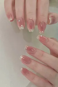 Dettaglio di unghie finte rosa nude sfumate con punte marmorizzate e strass luccicanti