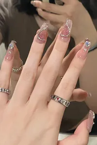 Close-up of pink cat eye press-on nails with heart rhinestones and silver chains