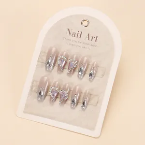 Cat-eye press-on nails with pink glitter gradient, rhinestones, and heart-shaped sequins