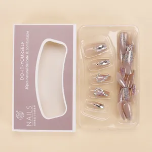 Close-up of pink glitter press-on nails with rhinestone accents and packaging box
