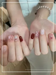 Close-up of red and pink short round press-on nails with cherry and bow patterns