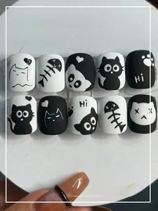 Detail view of black and white cartoon cat press-on nails on a white display tray