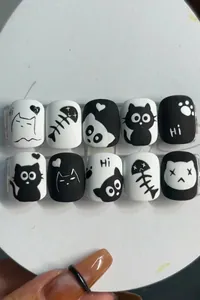 Close-up of matte black and white cartoon cat press-on nails with 24 pieces set