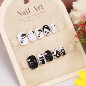 Detailed view of kids' black and white cartoon cat press-on nails with cute motifs