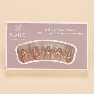 Detail of luxury press-on nails with pink gradient, fine glitter, and large rhinestones