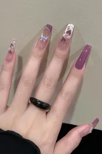 Detail of long ballerina nails with purple cat-eye, heart charms, and pearl accents