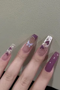 Detail of purple cat eye press-on nails with 3D white butterfly and pearl accents