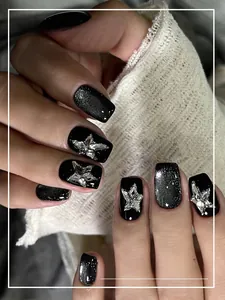 Detailed close-up of short black glitter press-on nails with silver rhinestone butterfly