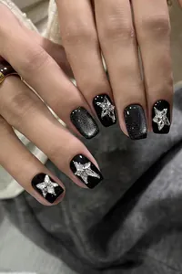 Close-up of black cat-eye press-on nails with shimmering silver star rhinestones