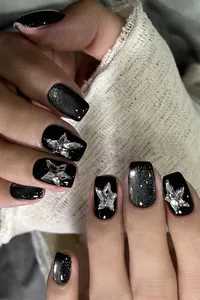 Close-up of black glitter press-on nails with silver star and butterfly 3D crystals