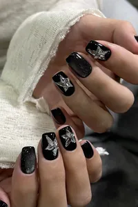Detail of black press-on nails with silver glitter, stars, and 3D rhinestone accents