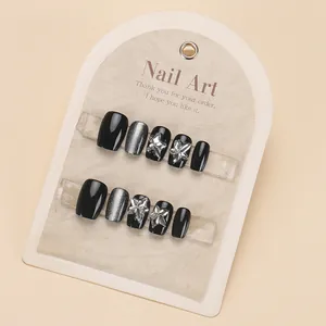 Detail view of 10pcs black sparkly press-on nails with silver cat-eye and 3D crystal bows