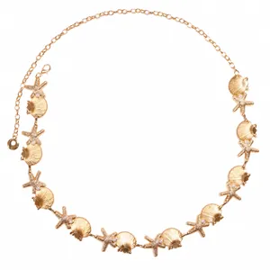 Detail of bohemian gold alloy waist chain with shells, starfish, and white pearls