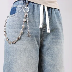 Detail of punk metal pants chain featuring skull links and a vintage fleur-de-lis pendant