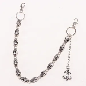 Close-up of retro silver skull chain links with a detailed fleur-de-lis pendant detail