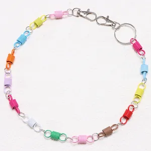 Detail of colorful spring keychain with dual metal lobster clasps and ring on white surface