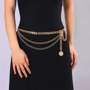 Détail d'une chaîne de taille dorée multicouche avec trois rangs et pendentif pièce de monnaie