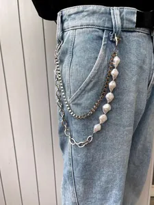 Detail of hip-hop waist chain featuring layered metal links and white pearls on denim