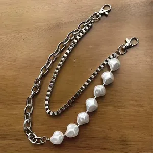 Detailed close-up of hip hop pearl and silver metal layered waist chain on wooden background