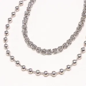 Detailed close-up of a silver metal ball chain and a Byzantine-style braided trouser chain