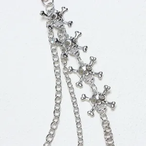 Détail macro d'une chaîne gothique en métal argenté avec pendentifs têtes de mort