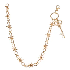 Detail van gouden punk tailleketting met prikkeldraadontwerp en kroonsleutel hanger