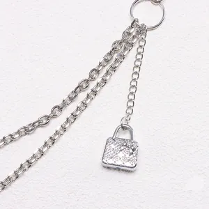 Detail of silver layered metal waist chains with a bow-knot handbag pendant