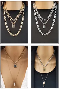 Detail of layered gold and silver chains featuring a heart key and LOVE padlock pendant