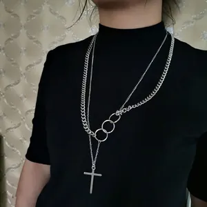 Layered silver necklace with curb chain, triple interlocking rings, and a cross pendant