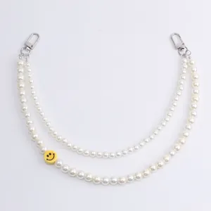 Dubbellaagse witte parelketting met een gele smiley-bedel en zilveren karabijnsluitingen
